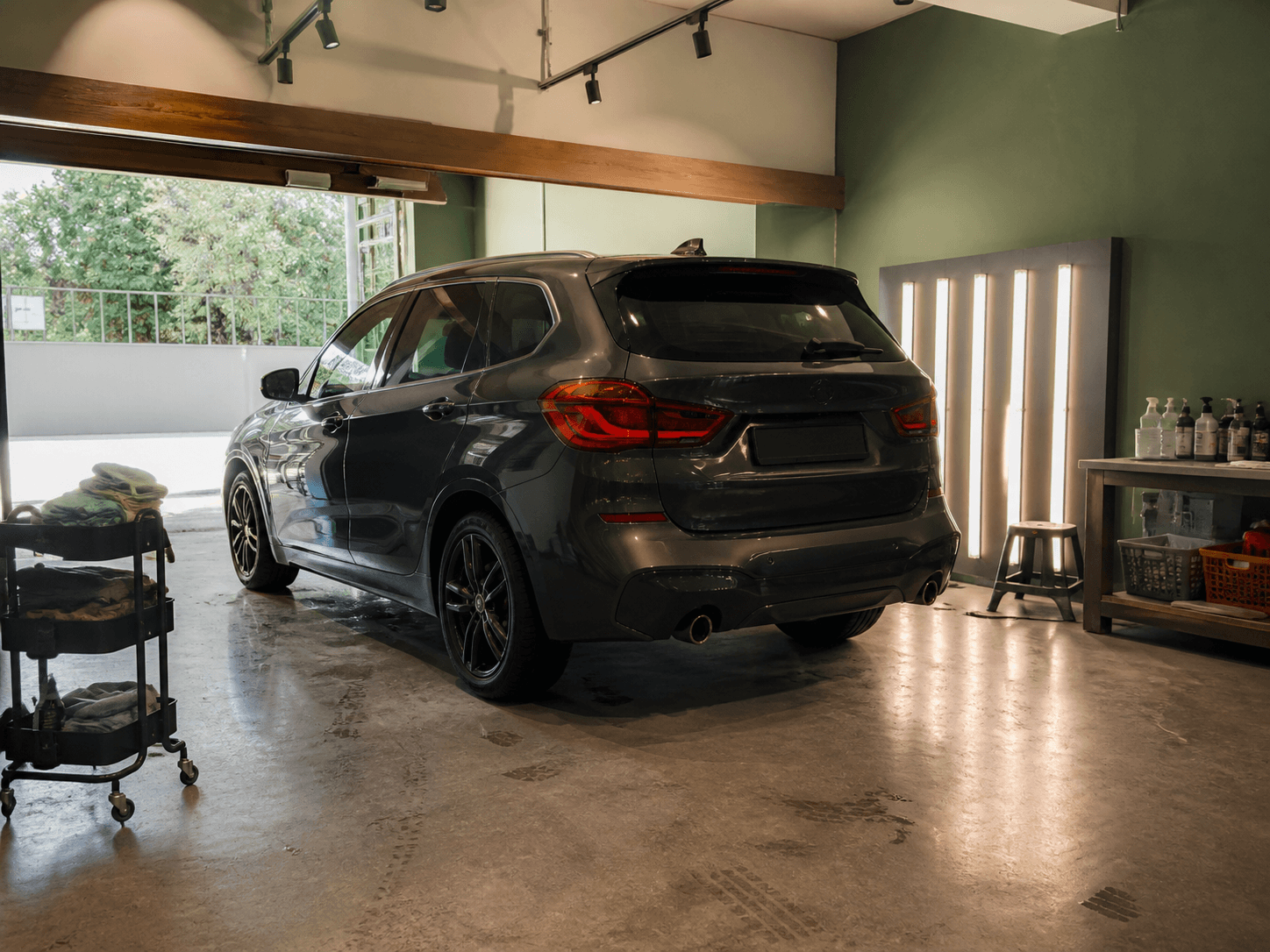 Vehicle preparation bay with an SUV, inspection lights, and everyday workshop details